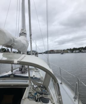 A recreational cruising sailboat moving peacefully across calm waters, highlighting standard running rigging setups.