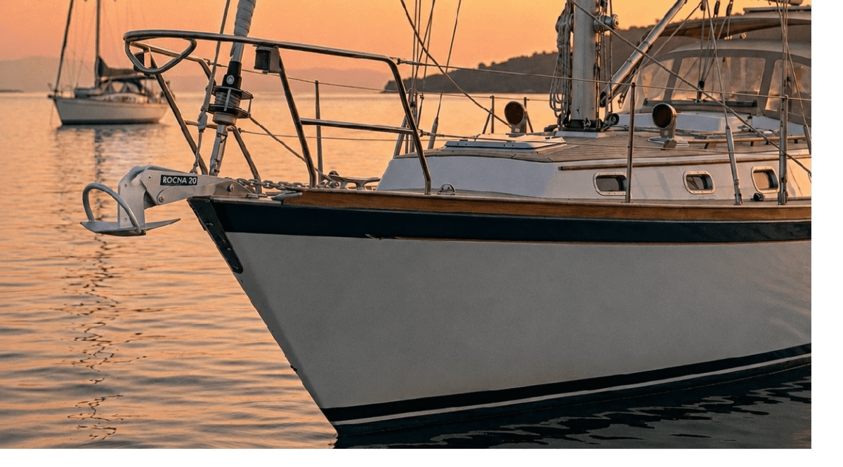 A Rocna boat anchor equipped with its signature roll-bar sitting on a boat bow roller, ready for deployment.