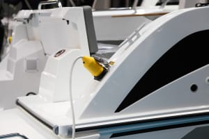 Marine shore power cable plugged into a powerboat at the dock to charge the onboard battery bank.
