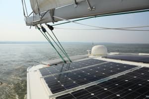 Close-up of marine-grade solar panels installed on a sailboat deck, demonstrating a clean energy setup for charging house batteries.