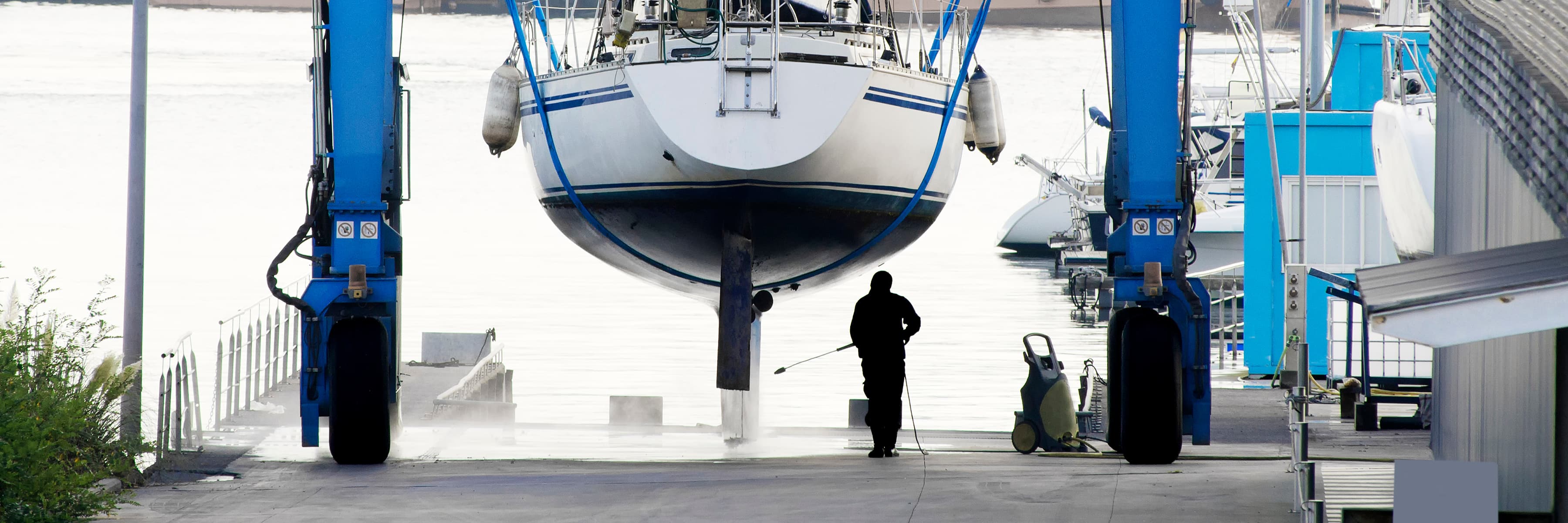 Sailboat being lifted out of the water by a travel lift for hull maintenance.