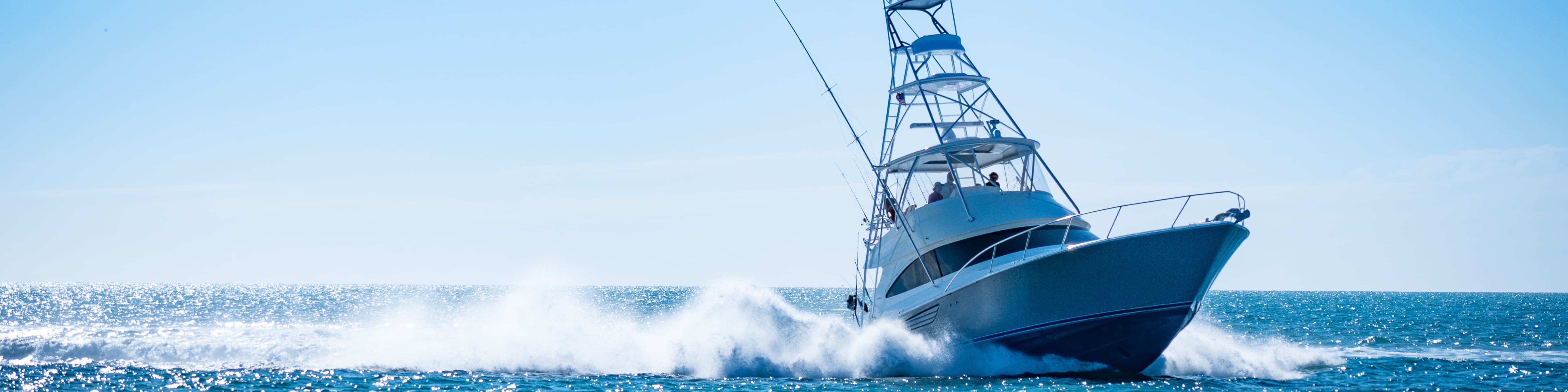 A recreational powerboat cruising in the open ocean under clear blue skies, representing safe maritime travel through proper gear preparation.